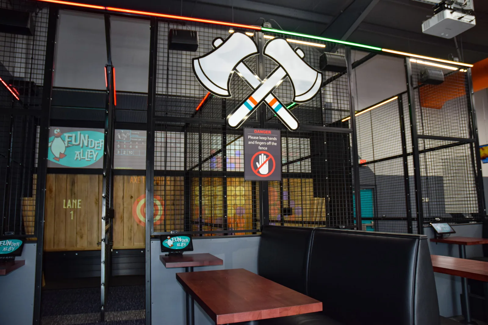 Funder Alley's Laser-Tron axe throwing cages with booth seating alongside