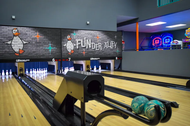 Duckpin balls waiting on the ball return beside a lane