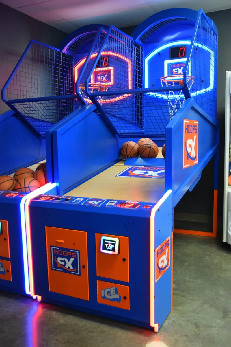 The neon-lit arcade basketball machines with balls racked and ready