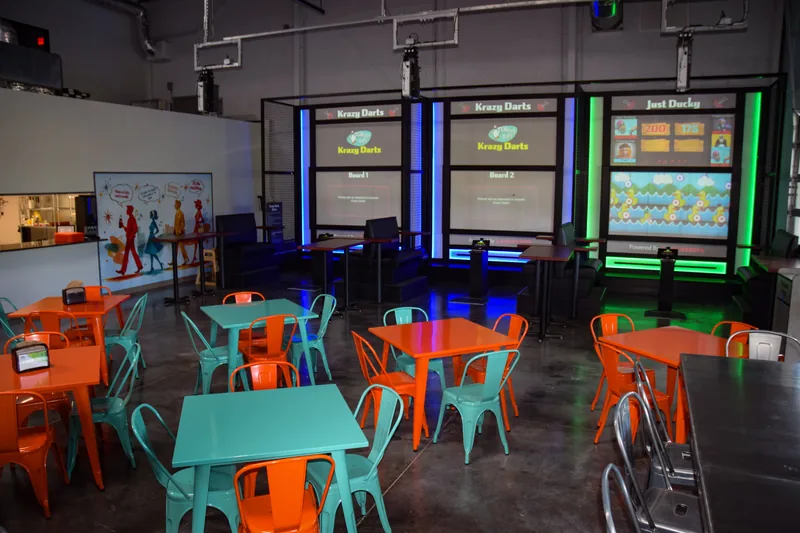 The Krazy Darts bays with orange and teal cafe tables in the foreground