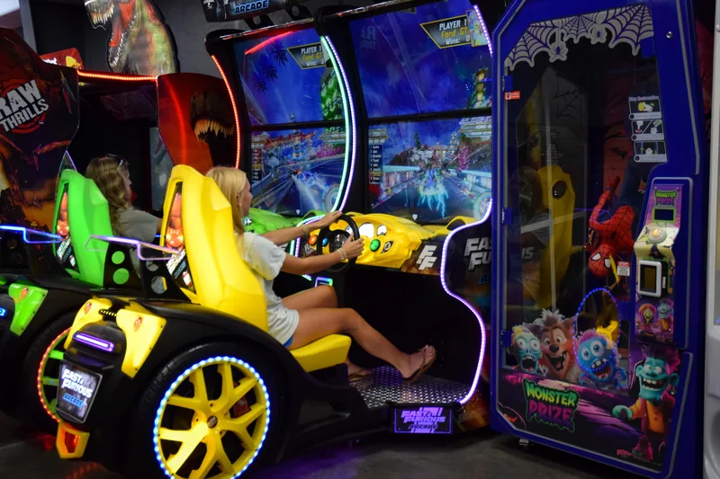 Two players side by side in the arcade's racing game cabinets